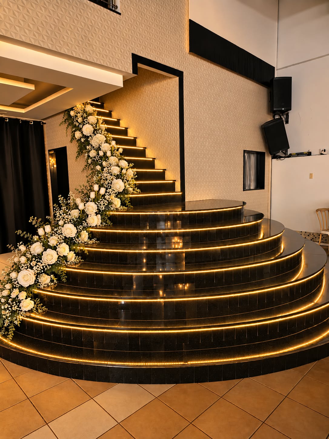 Escadaria decorada com flores e iluminação dourada na Casa de Festas Lofty King